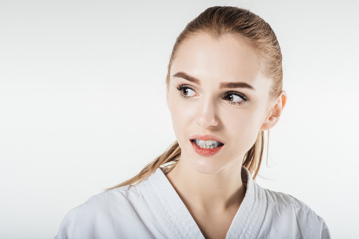 Young woman in dental uniform smiling at camera against white background.